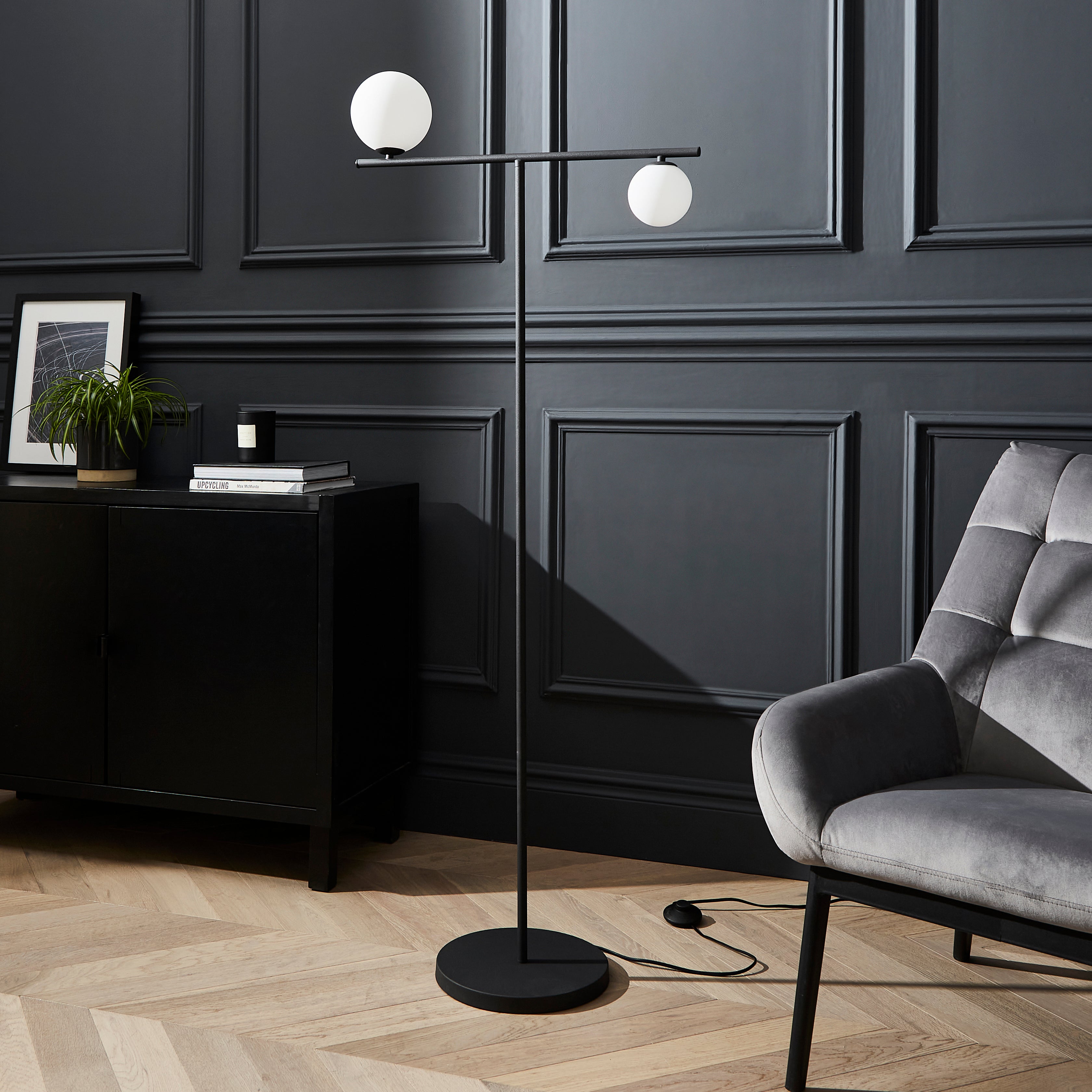 Modern black floor lamp with two white globe lights in a living room setting.