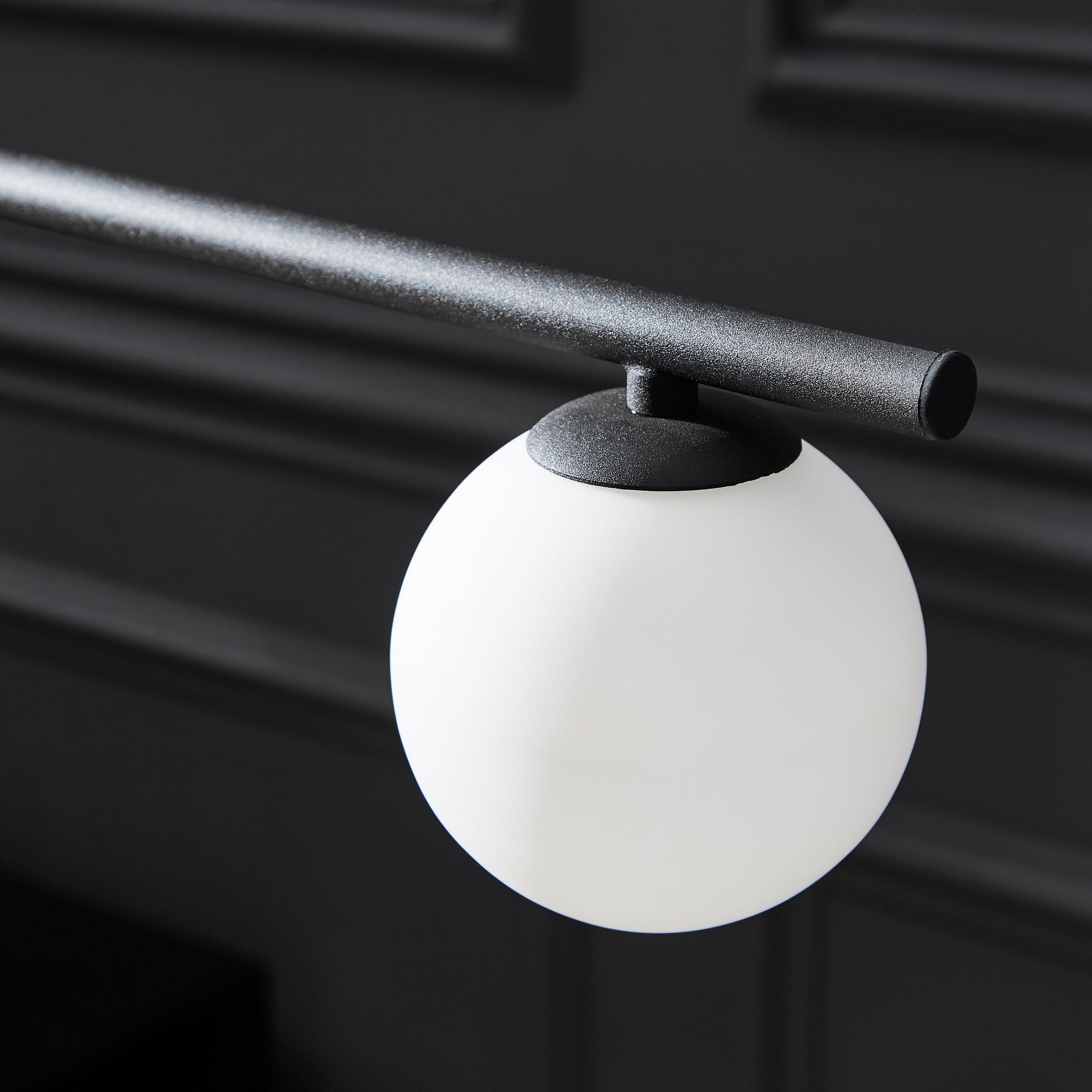 White spherical light fixture with black top on a dark background
