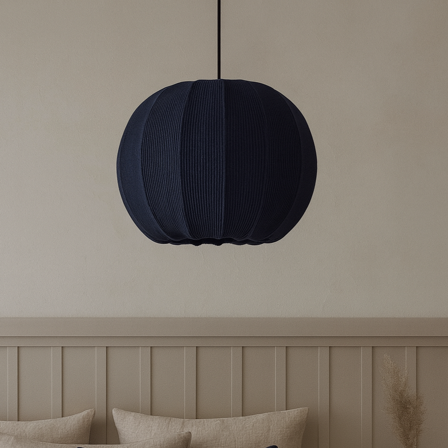 Navy pendant light above a bed with beige bedding and pillows.