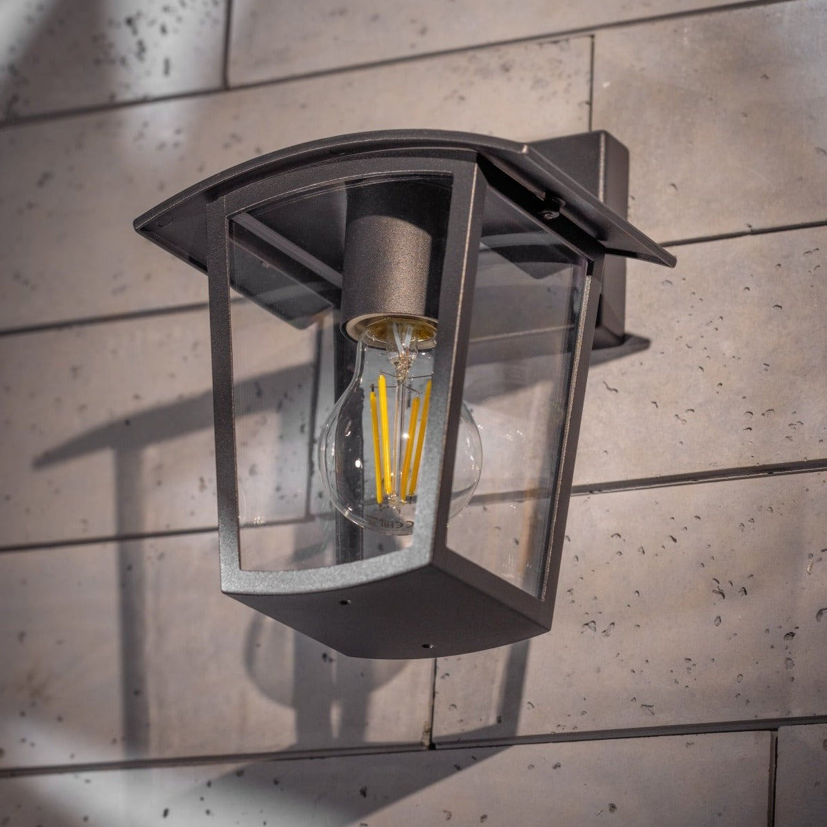 If you’re looking for a modern take on a traditional outdoor wall light, this black lantern wall light with clear diffuser is perfect for adding style and protection for your home. This classic design with a contemporary twist, styled with a metal lantern shape and fitted with clear polycarbonate diffusers that allows the light to shine effectively. This product also contains an imposing black finish, making it ideal for any home design - adding a statement to any wall it fits in