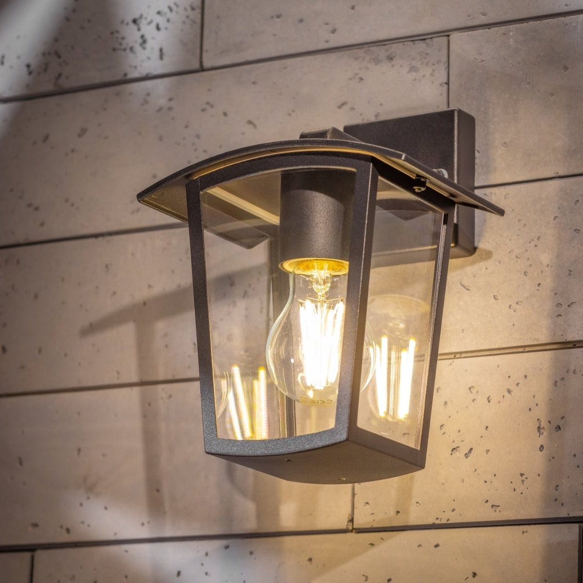 If you’re looking for a modern take on a traditional outdoor wall light, this black lantern wall light with clear diffuser is perfect for adding style and protection for your home. This classic design with a contemporary twist, styled with a metal lantern shape and fitted with clear polycarbonate diffusers that allows the light to shine effectively. This product also contains an imposing black finish, making it ideal for any home design - adding a statement to any wall it fits in