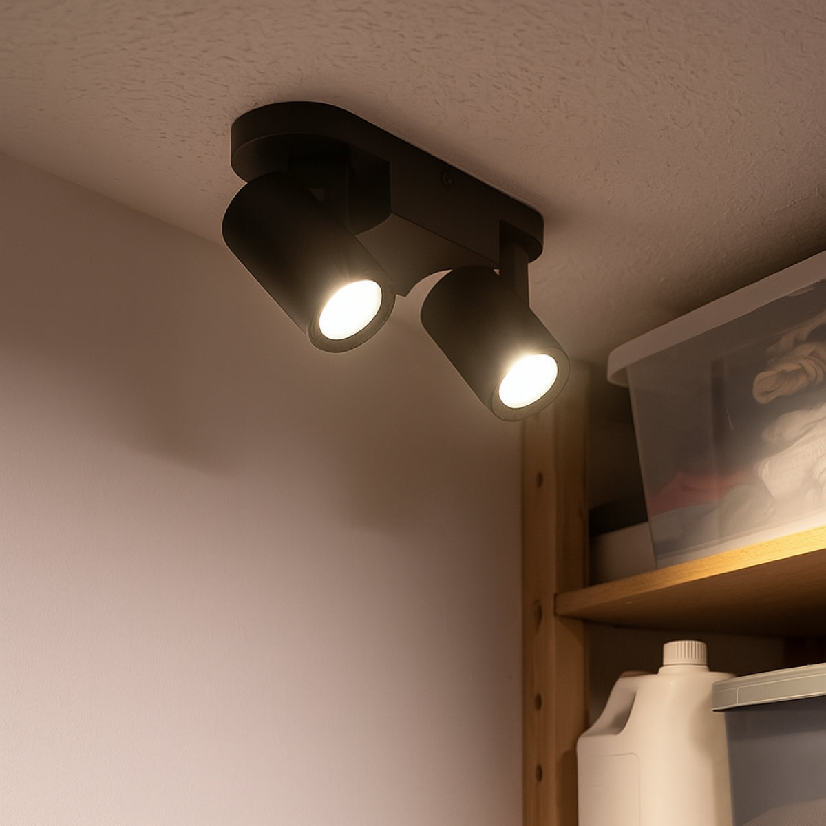 Black ceiling light fixture with two lights on a neutral wall.