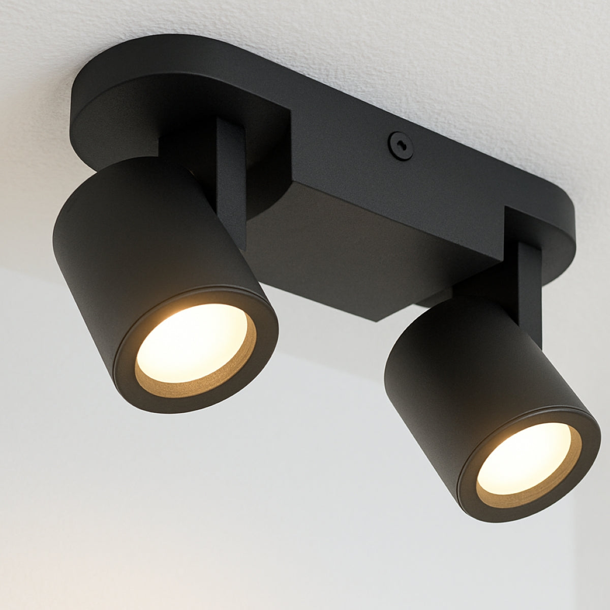Black ceiling light fixture with two illuminated lights on a white background