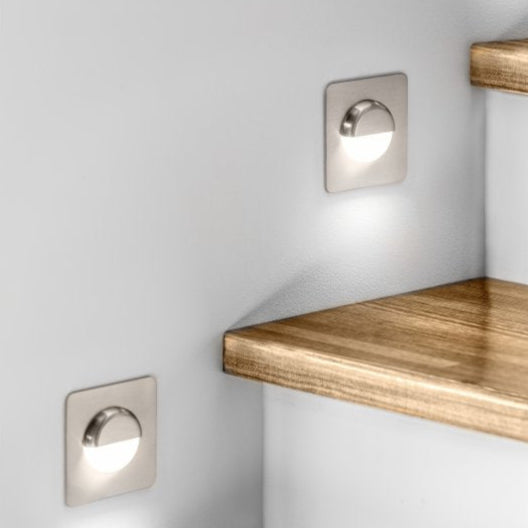 Wooden shelves with built-in wall lights on a white wall.