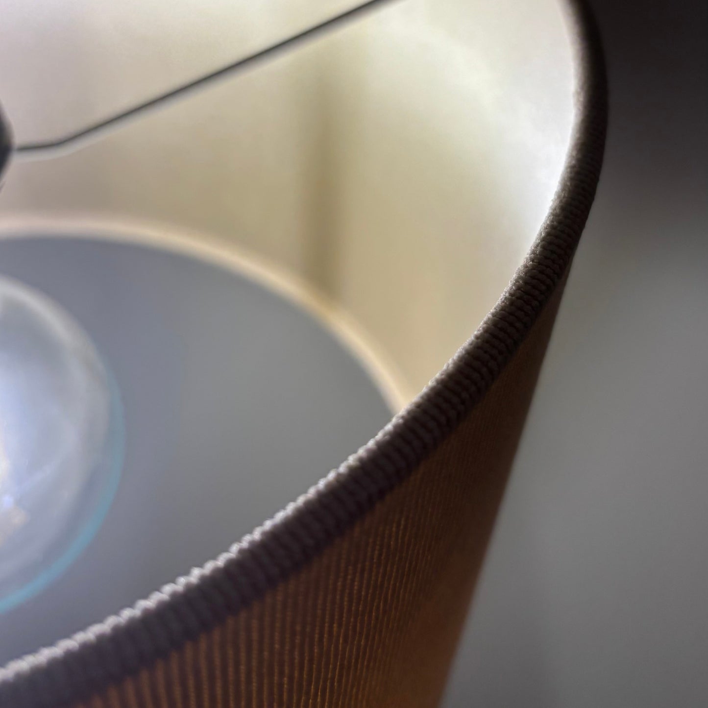 Close-up of a lampshade with a cream inner and textured surface and a dark background