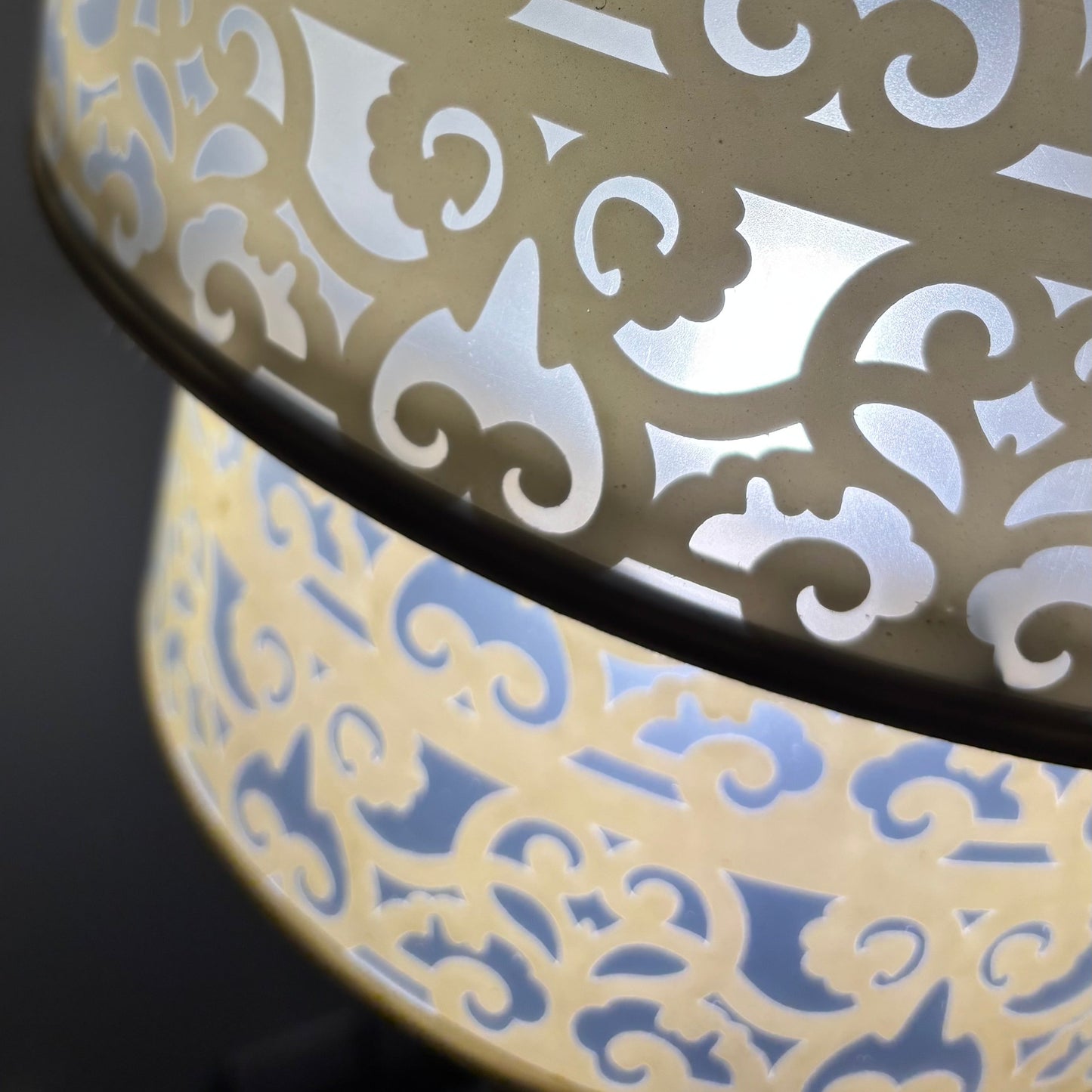 Decorative lampshade with intricate cut-out pattern on a dark background