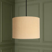Beige pendant lamp hanging against a green paneled wall