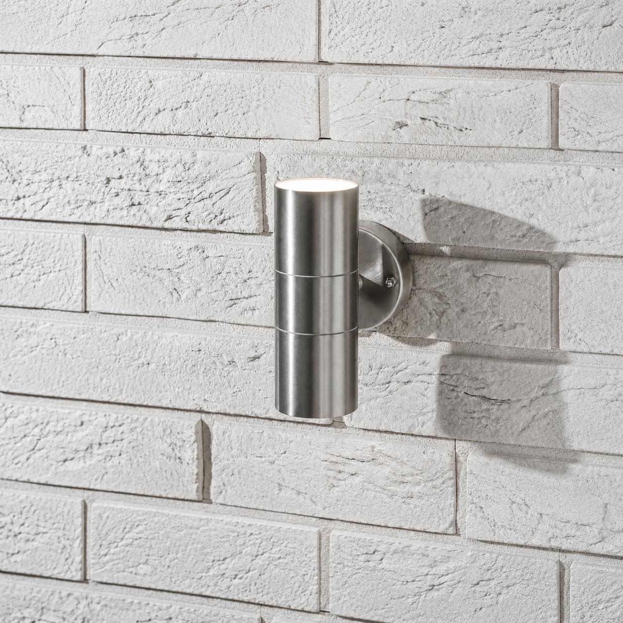 Modern CGC Interiors GU10 outdoor wall light in black aluminium casting warm light on textured brick.