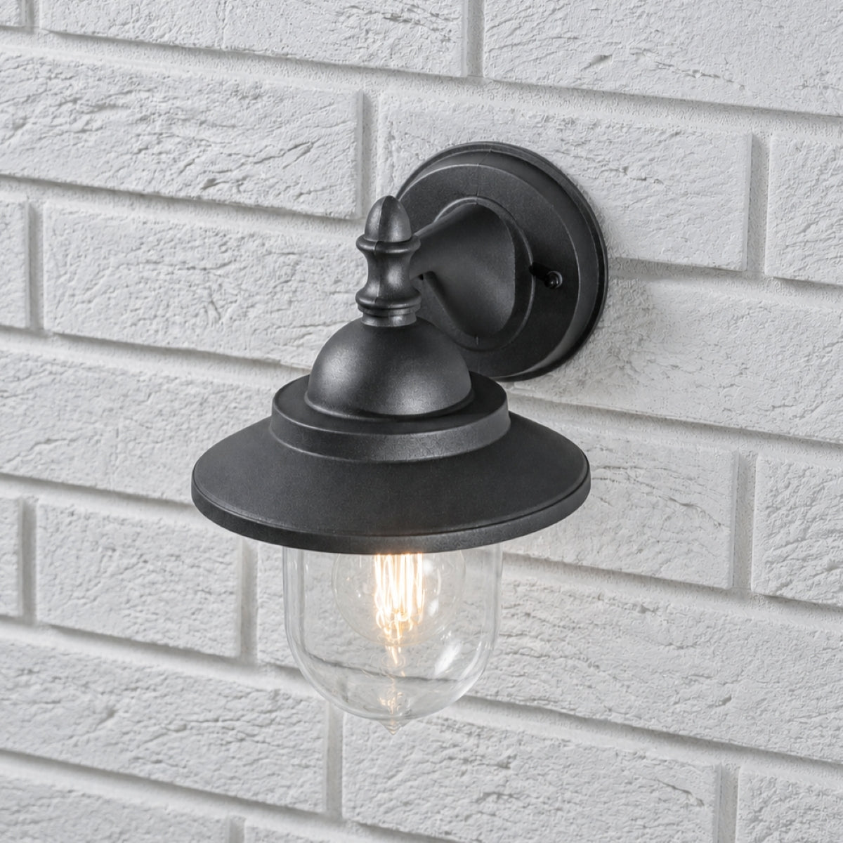 Black rectangular E27 outdoor wall light with exposed filament bulb mounted on grey brick wall.