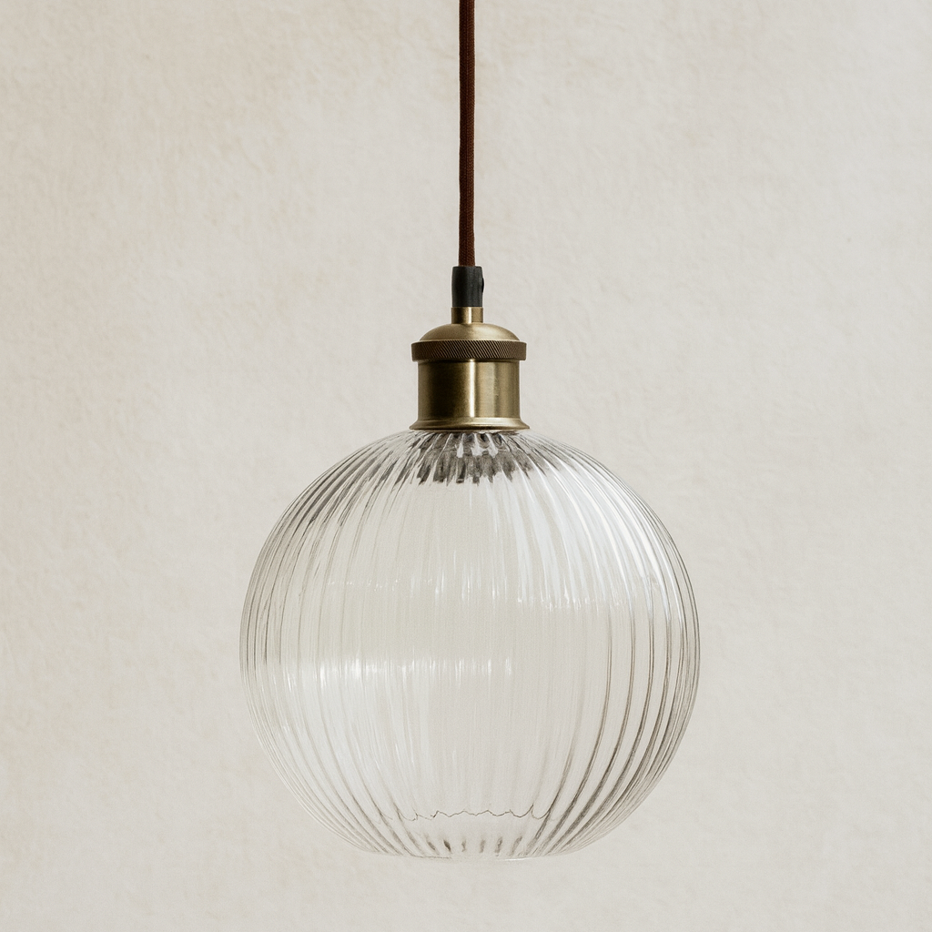 Clear glass pendant light with brass fixture on a neutral background