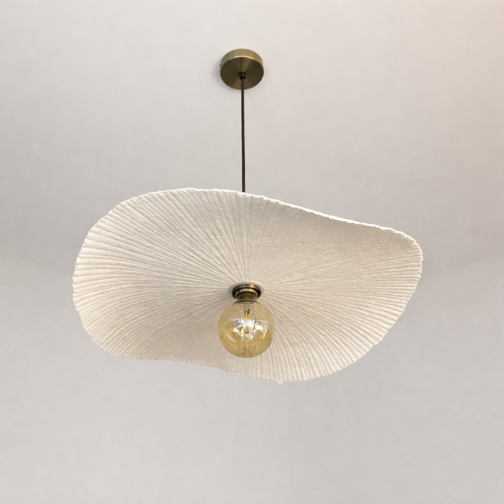 Ceiling light fixture with textured white shade and gold bulb on a plain background