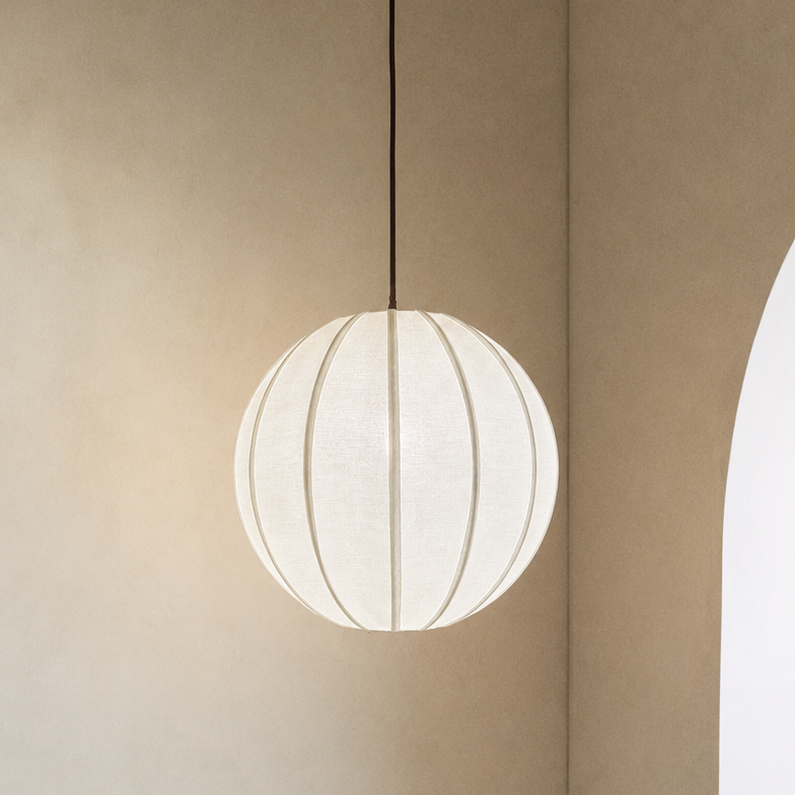 Spherical pendant light hanging in a minimalistic room with beige walls and a white arch.