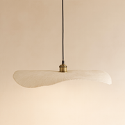 Beige pendant lamp with a gold bulb holder on a beige background