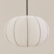 A modern spherical pendant light with a textured, pleated fabric shade in a warm off-white color, suspended by a thin black cord against a solid beige background.