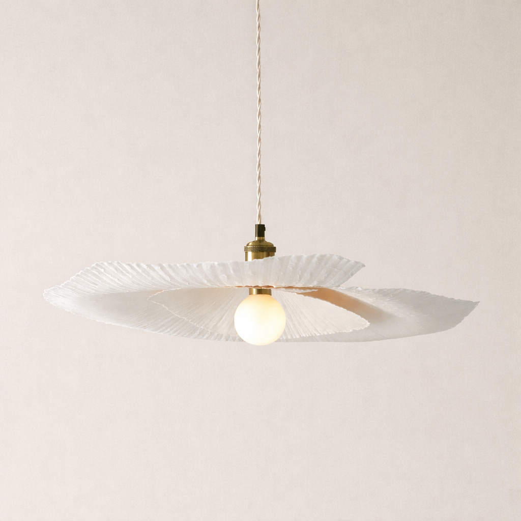 Pendant light with a white paper shade and gold fixture on a plain background