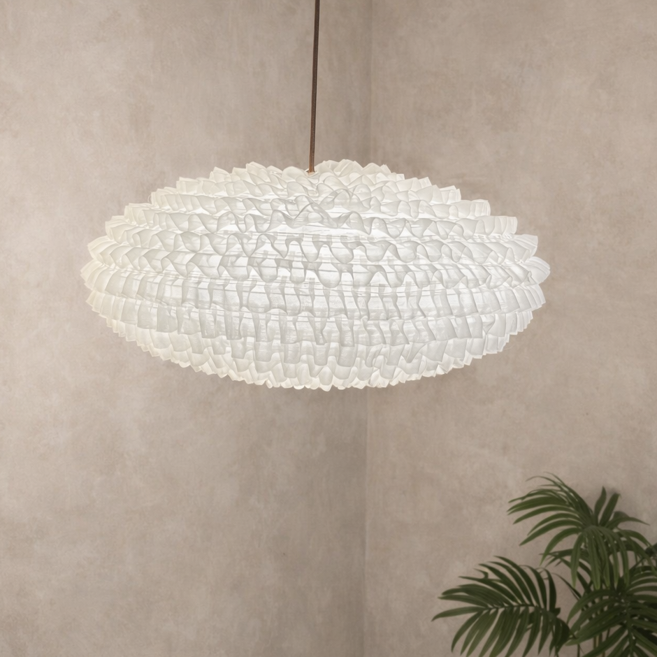 Large pendant light fixture hanging in a room with a plant on a neutral wall.