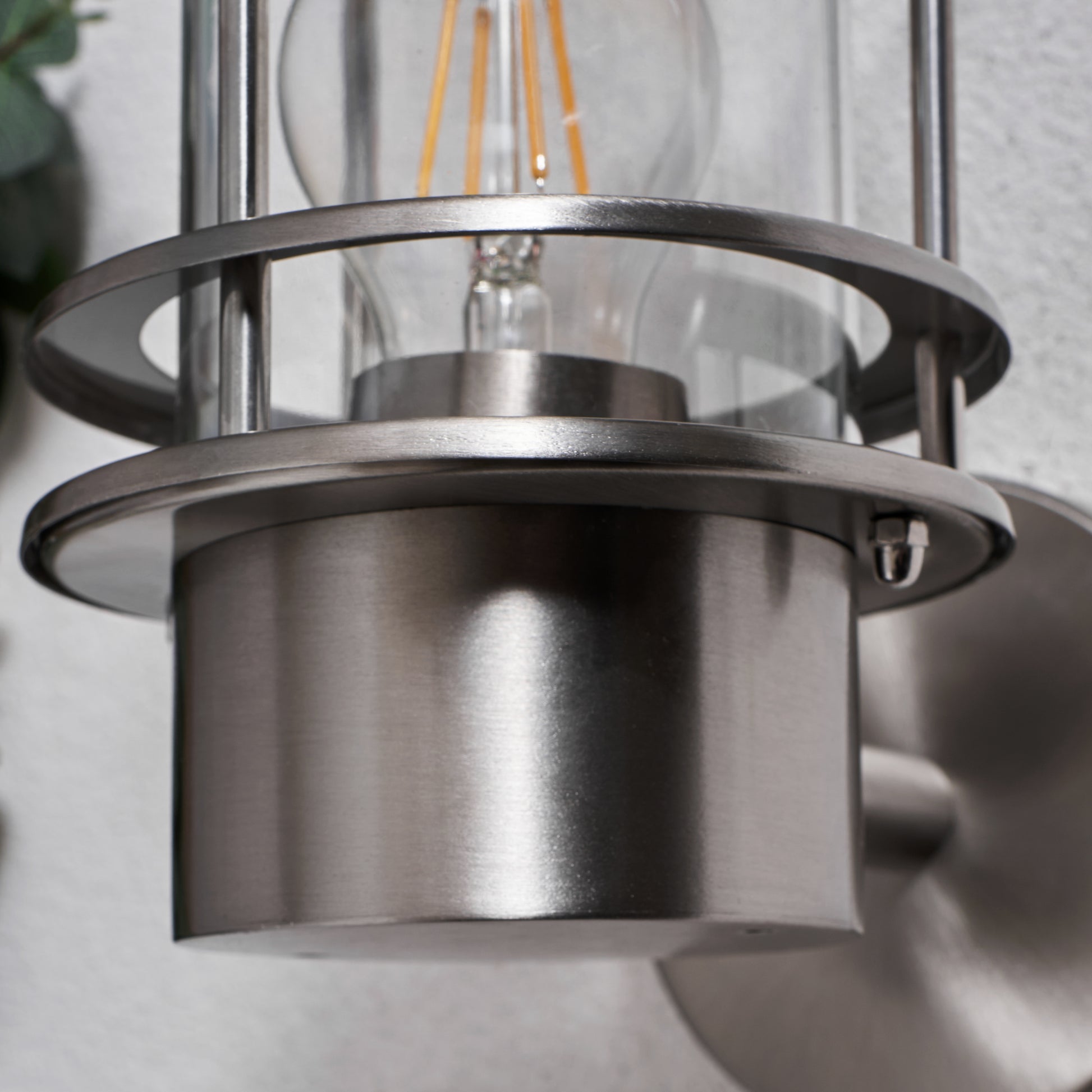 Metallic pendant light fixture with clear glass shade on a neutral background