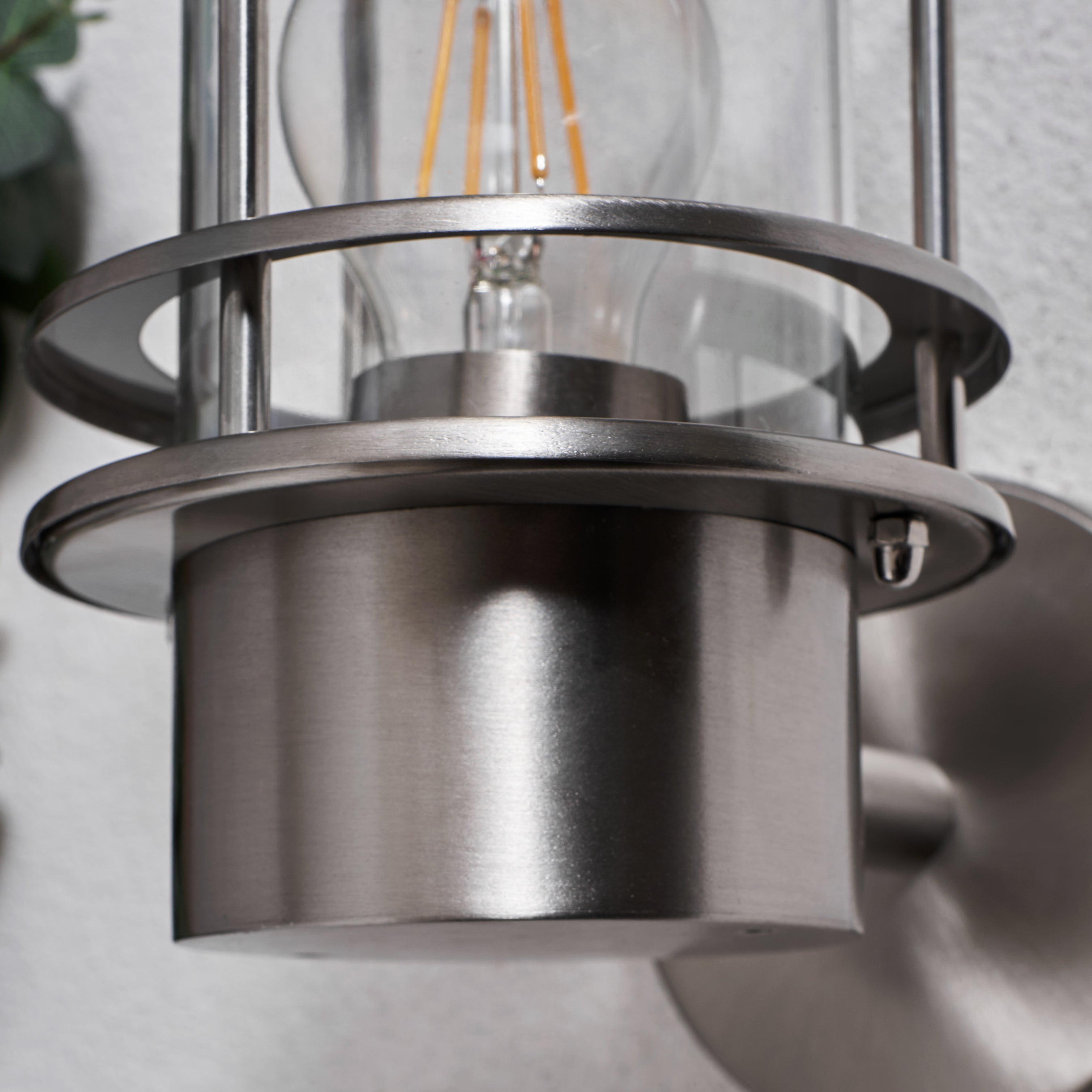 Metallic pendant light fixture with clear glass shade on a neutral background