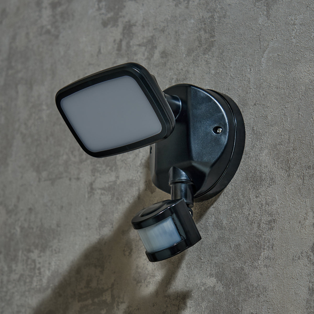 Outdoor security camera with motion sensor on a concrete wall