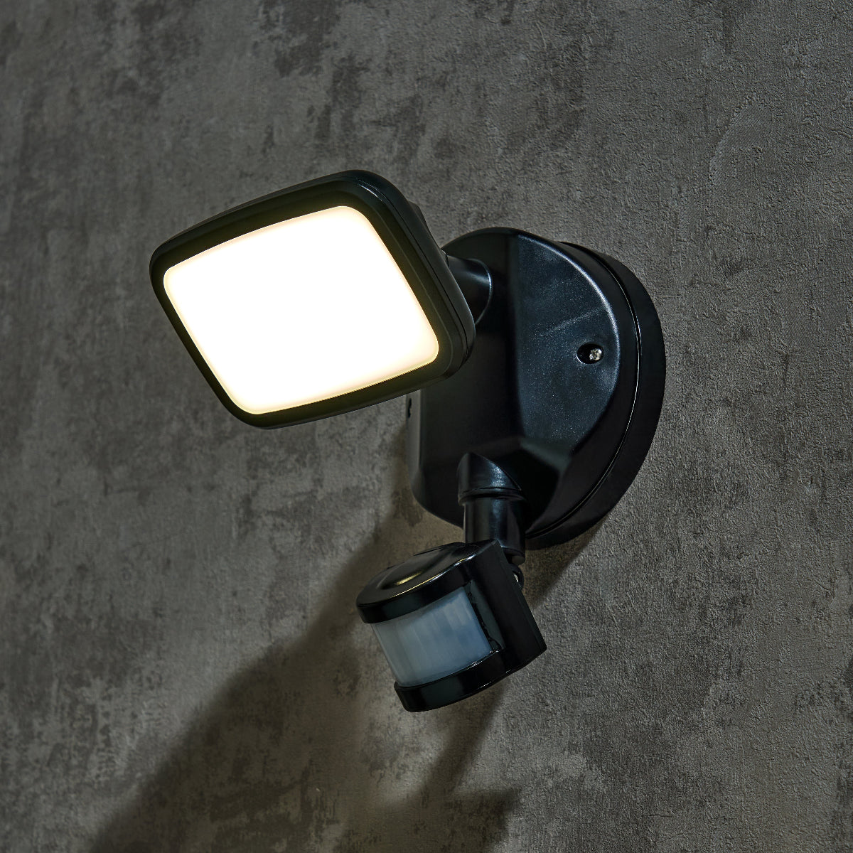 Outdoor security light with motion sensor on a concrete wall