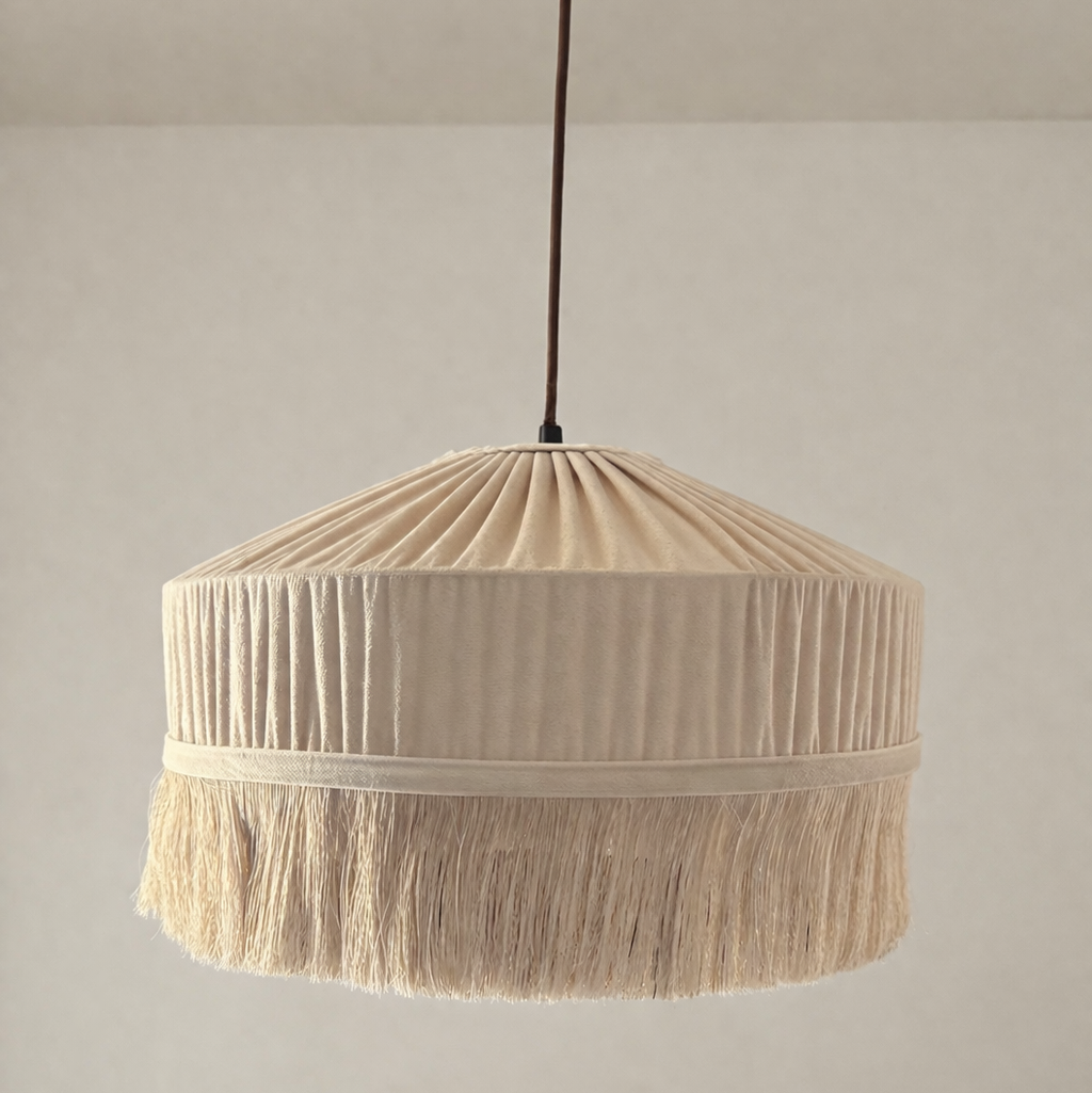 Beige pleated lampshade with tassels on a plain background