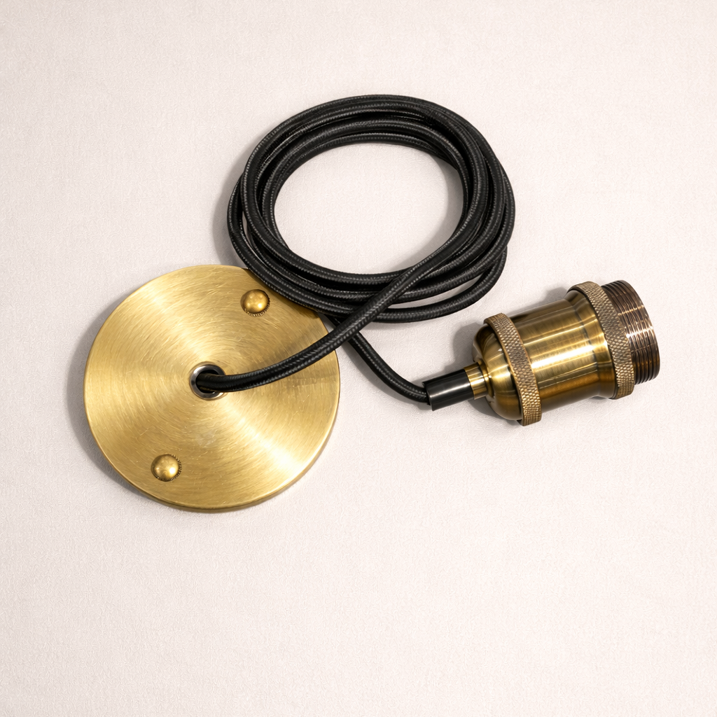 Brass lamp component with black cable on a beige background