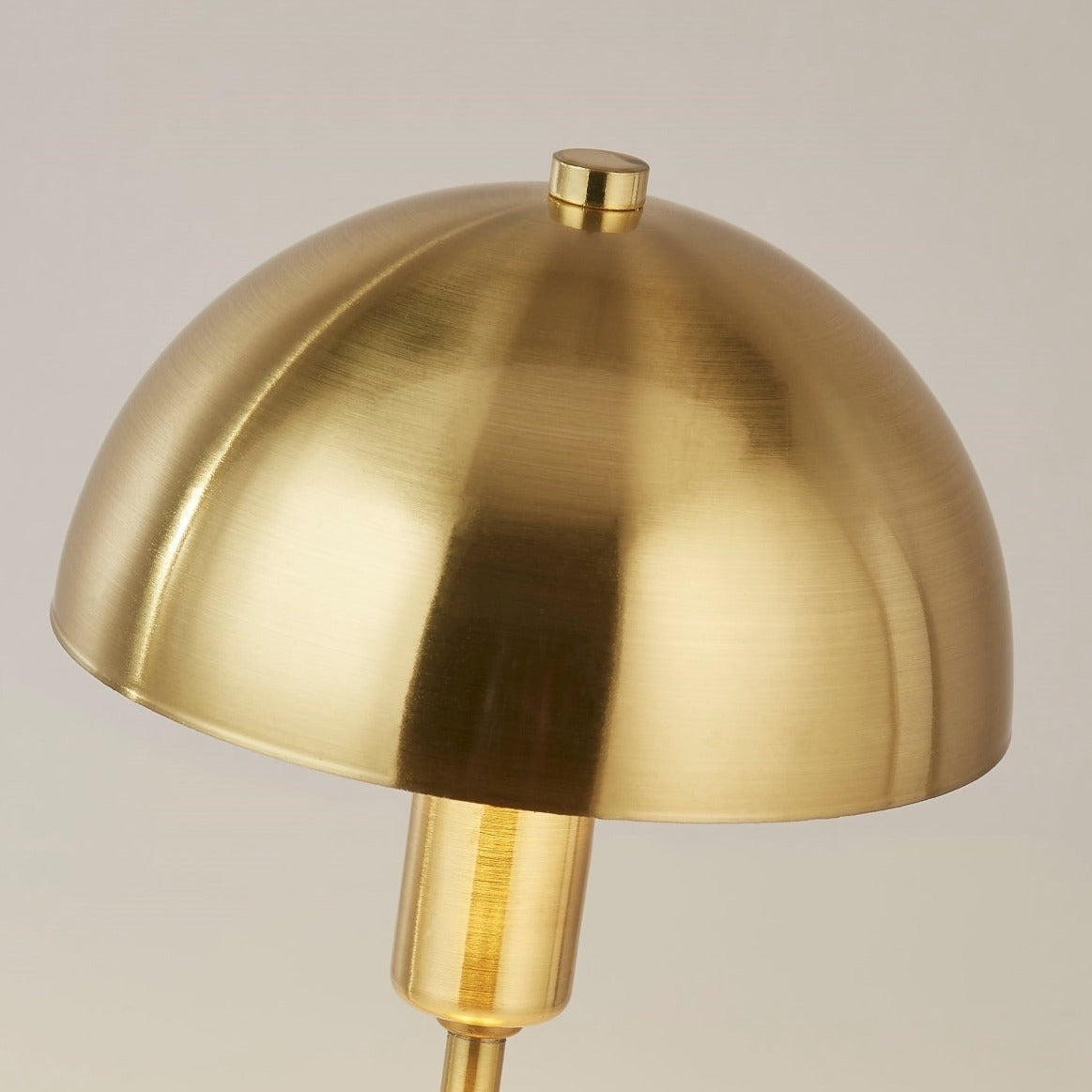 Our Nellie table lamp is a strong visual addition to your space with its distinctive dome-shaped shade and metal frame. Thanks to its brushed gold brass metal finish, it will suit both modern and traditional homes and commercial properties. Light reflects off the shade to enhance a warm and inviting glow.
