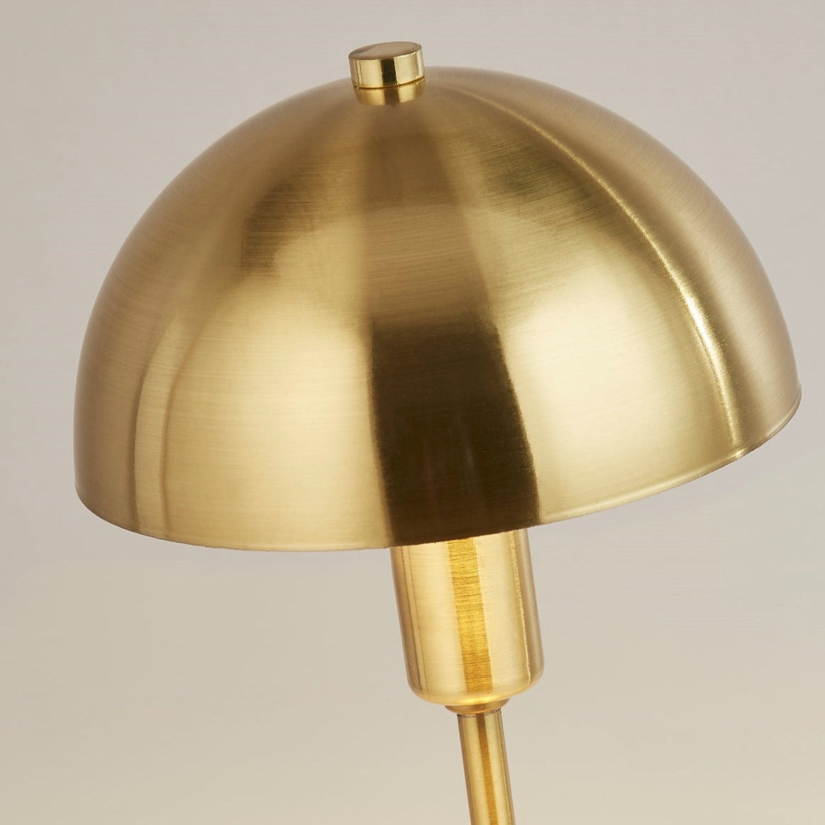 Our Nellie table lamp is a strong visual addition to your space with its distinctive dome-shaped shade and metal frame. Thanks to its brushed gold brass metal finish, it will suit both modern and traditional homes and commercial properties. Light reflects off the shade to enhance a warm and inviting glow.
