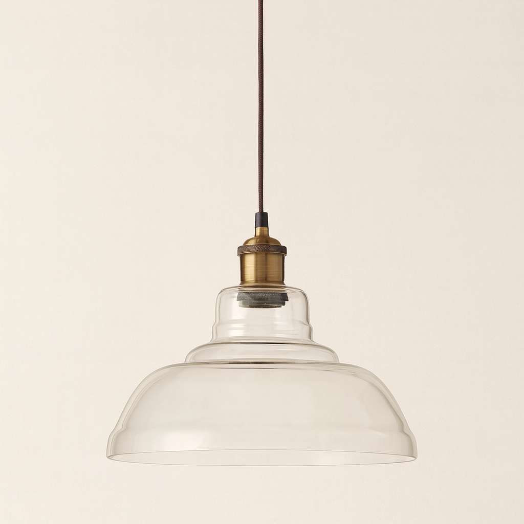 Pendant light with clear glass shade and brass fixture on a beige background