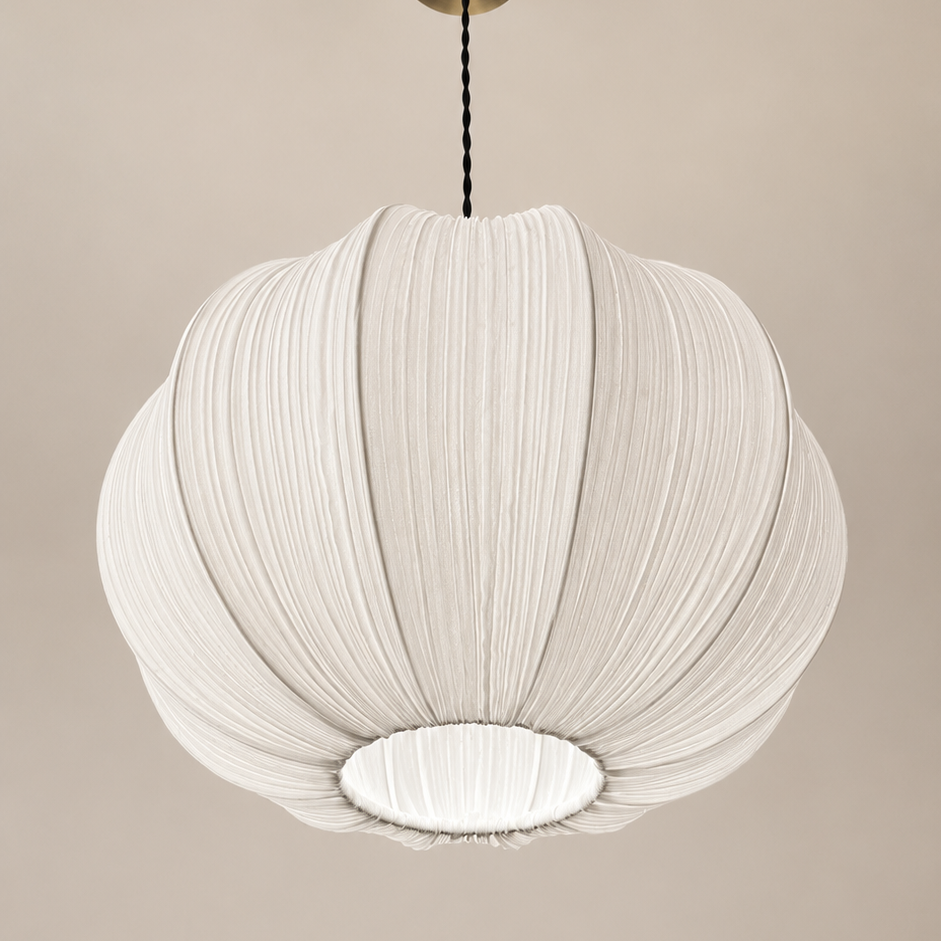 A modern white pleated pendant light with a ribbed, balloon-like design, suspended from a brass ceiling canopy against a warm beige wall.