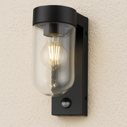 Black outdoor wall light fixture with clear glass cover on a textured wall.