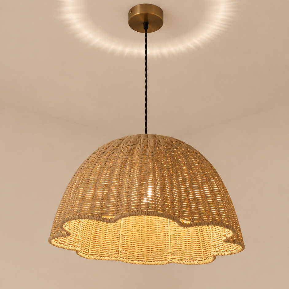 A woven natural rattan dome pendant light hanging from a brass ceiling canopy, casting a warm golden glow and a circular light pattern on the ceiling.