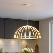 Modern pendant light hanging above a dining table with chairs in a kitchen setting.
