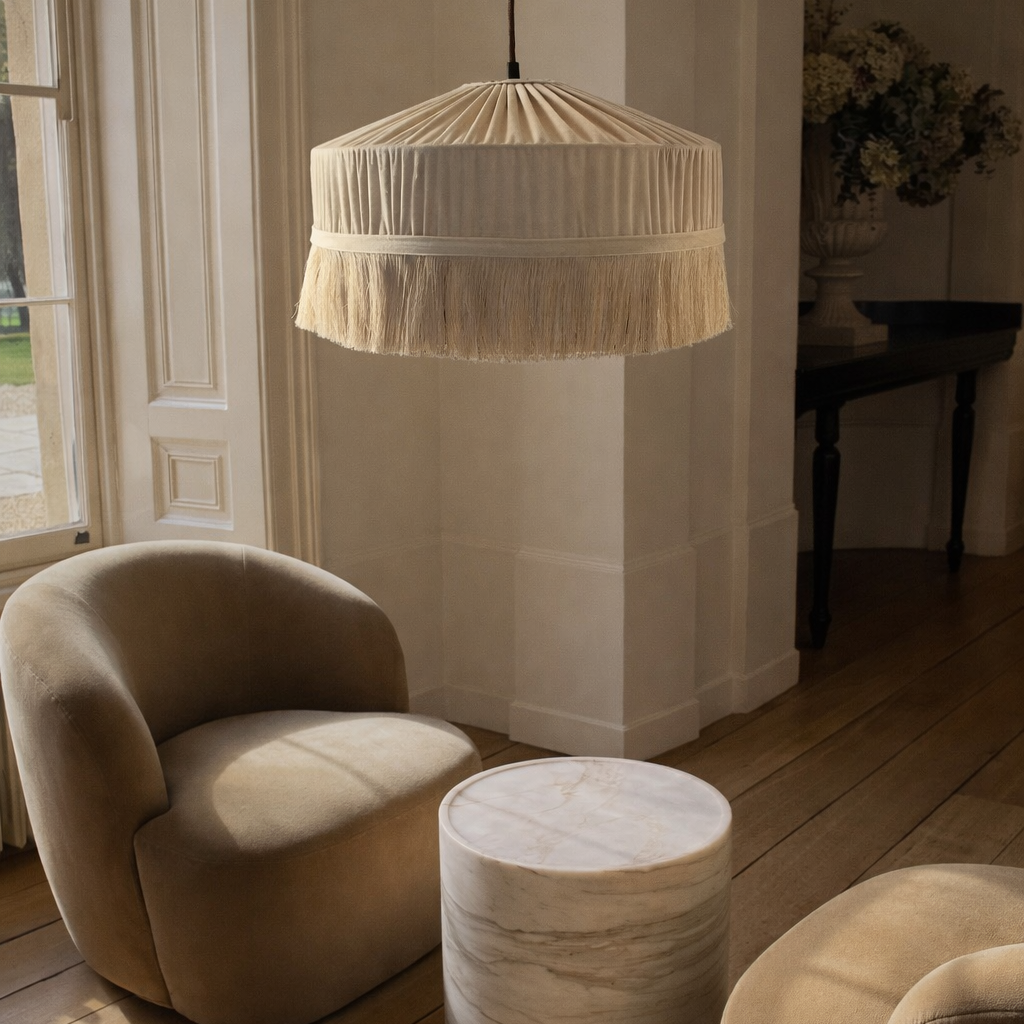 Beige armchair and ottoman with a textured pendant light in a room with wooden flooring and a window.