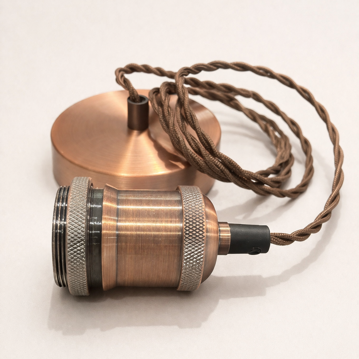 Copper pendant light with braided cable on a white background
