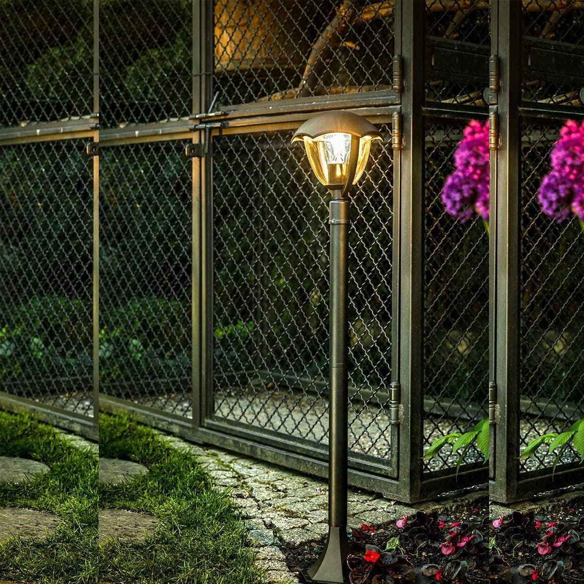 Garden lamp post with decorative flowers in front of a chain-link fence