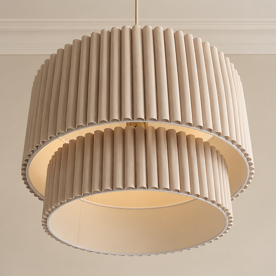 A two-tier drum pendant light fixture with pleated beige fabric shades and a warm cream interior, shown hanging against a neutral beige wall.