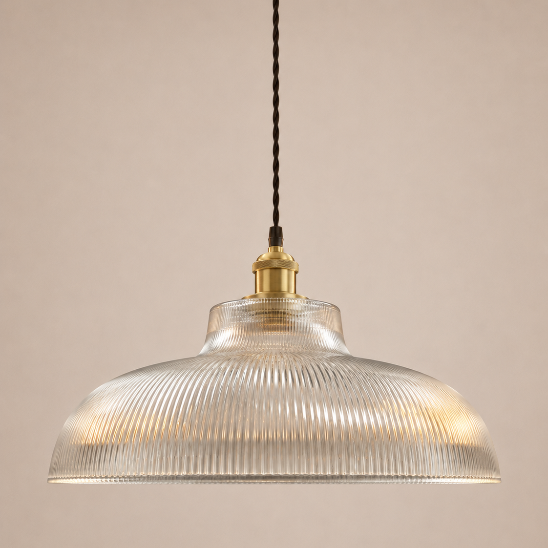 Pendant light with ribbed glass shade and brass fixture on a beige background