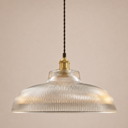 Pendant light with ribbed glass shade and brass fixture on a beige background