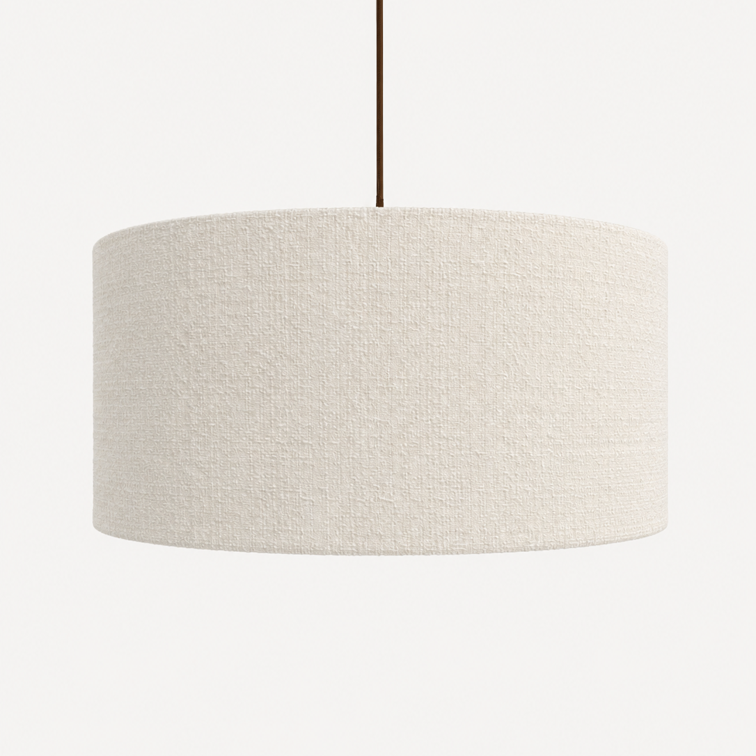 A drum-shaped pendant light shade made of textured cream-colored fabric, suspended by a thin dark cord against a plain light background.