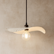 Modern pendant light with a unique design on a beige wall.
