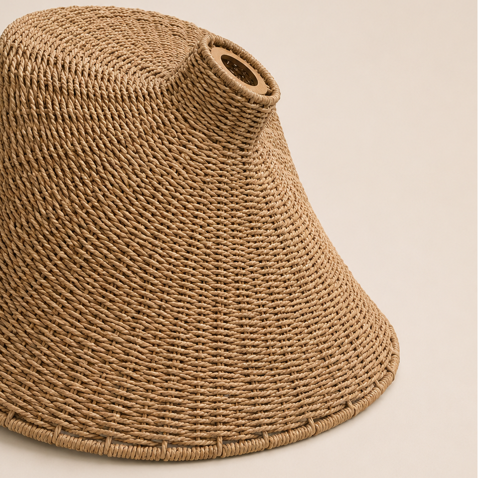 A natural woven straw lampshade with a flared conical shape and a small circular opening near the top, shown on a solid light beige background.