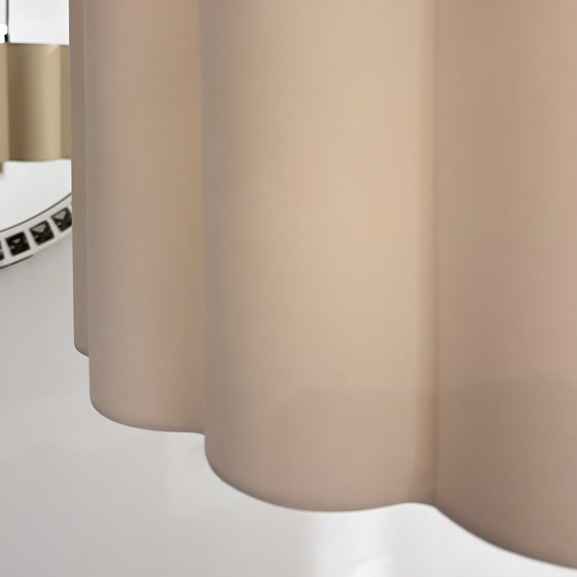 Close-up of a beige wavy lampshade with a mirror reflection.