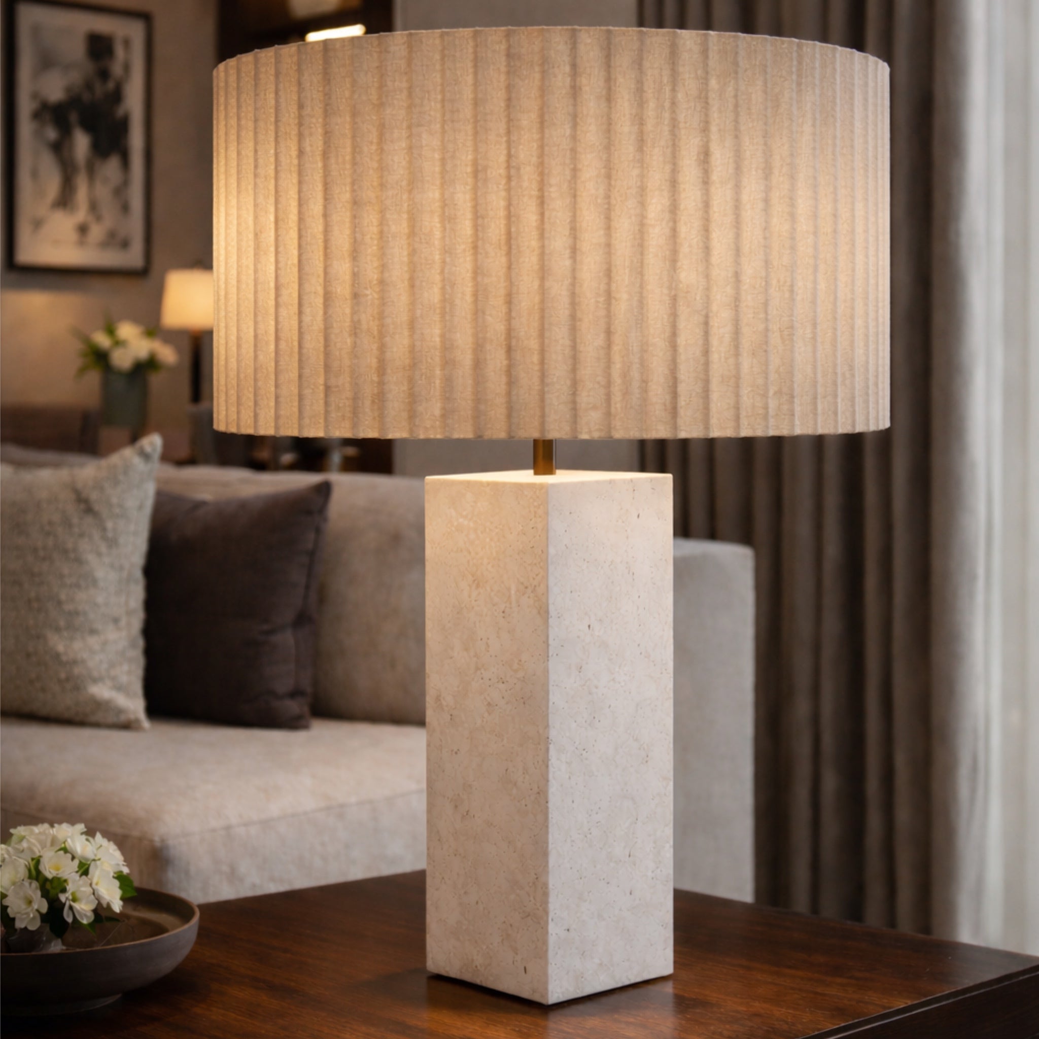 Table lamp with a textured shade on a wooden table in a living room setting.