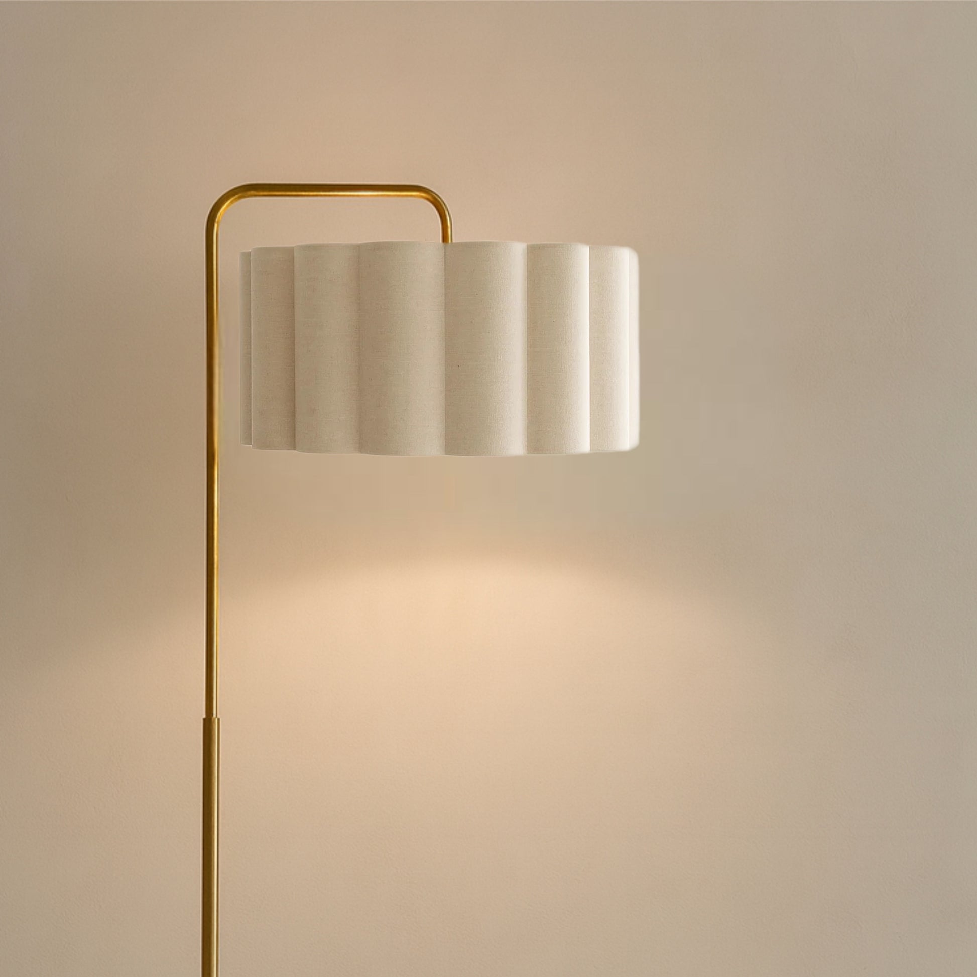 Floor lamp with a gold base and white shade on a beige background