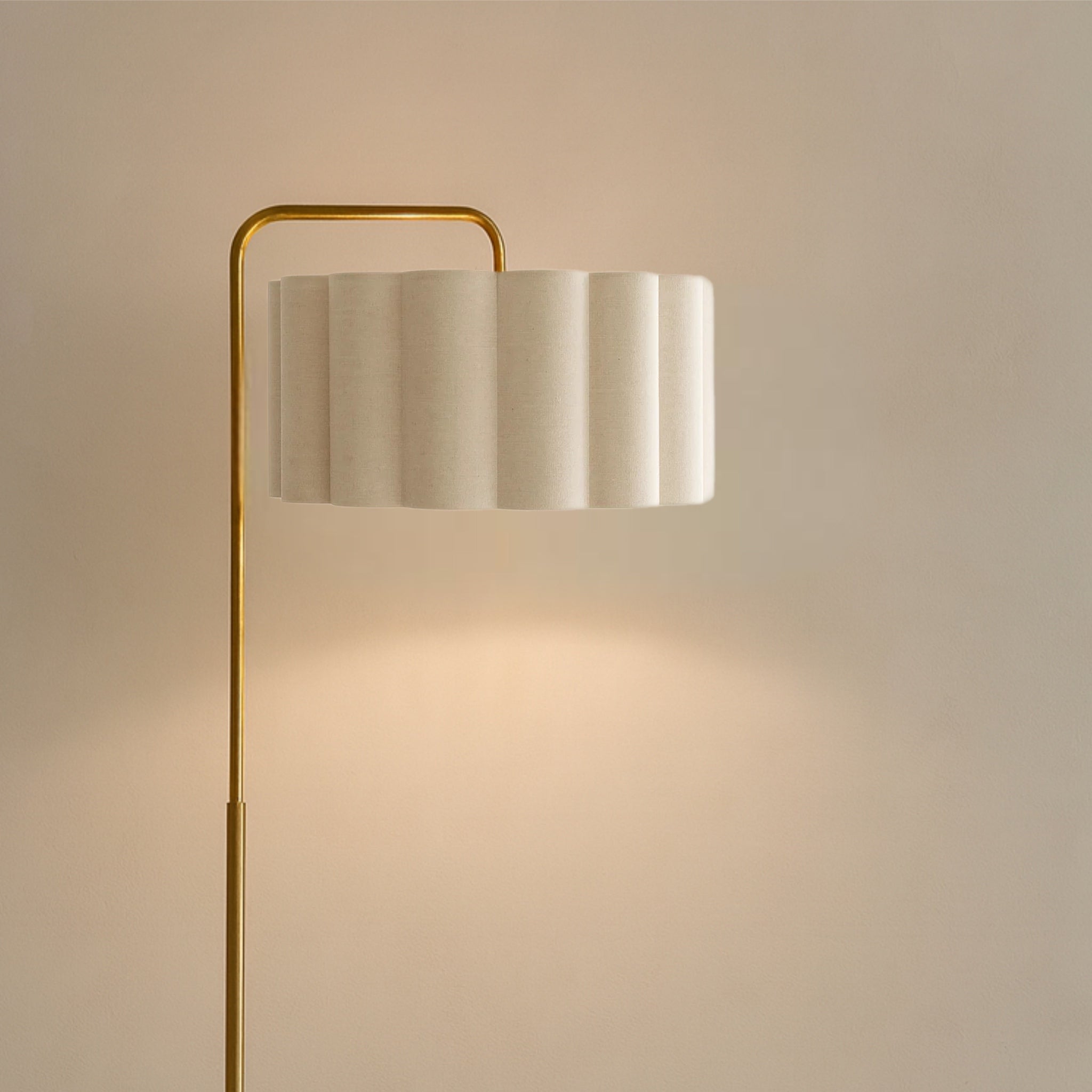 Floor lamp with a gold base and white shade on a beige background