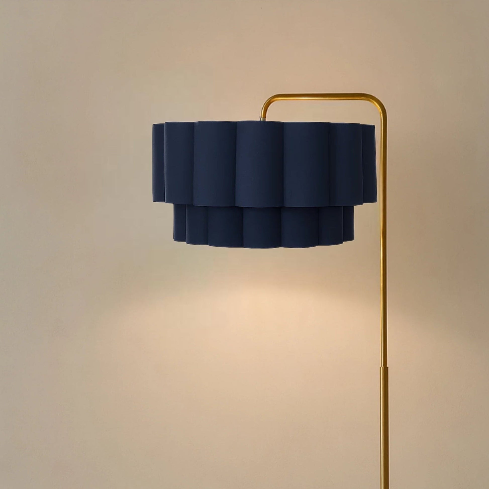 Floor lamp with a navy blue ruffled shade and gold base on a beige background