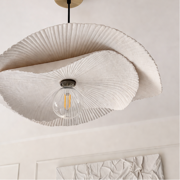 Modern ceiling light fixture with a decorative shade in a room with textured wall.