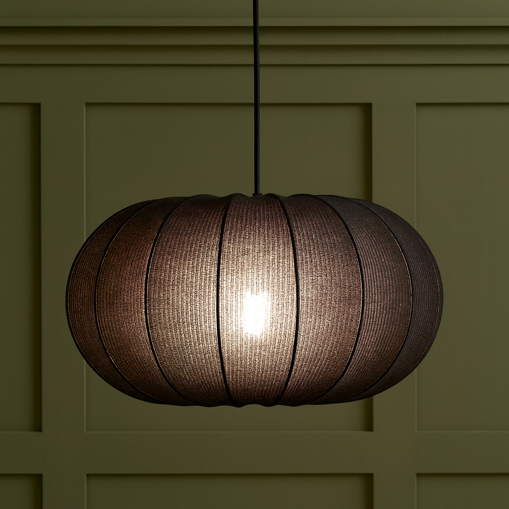 Round pendant light hanging against a green paneled wall