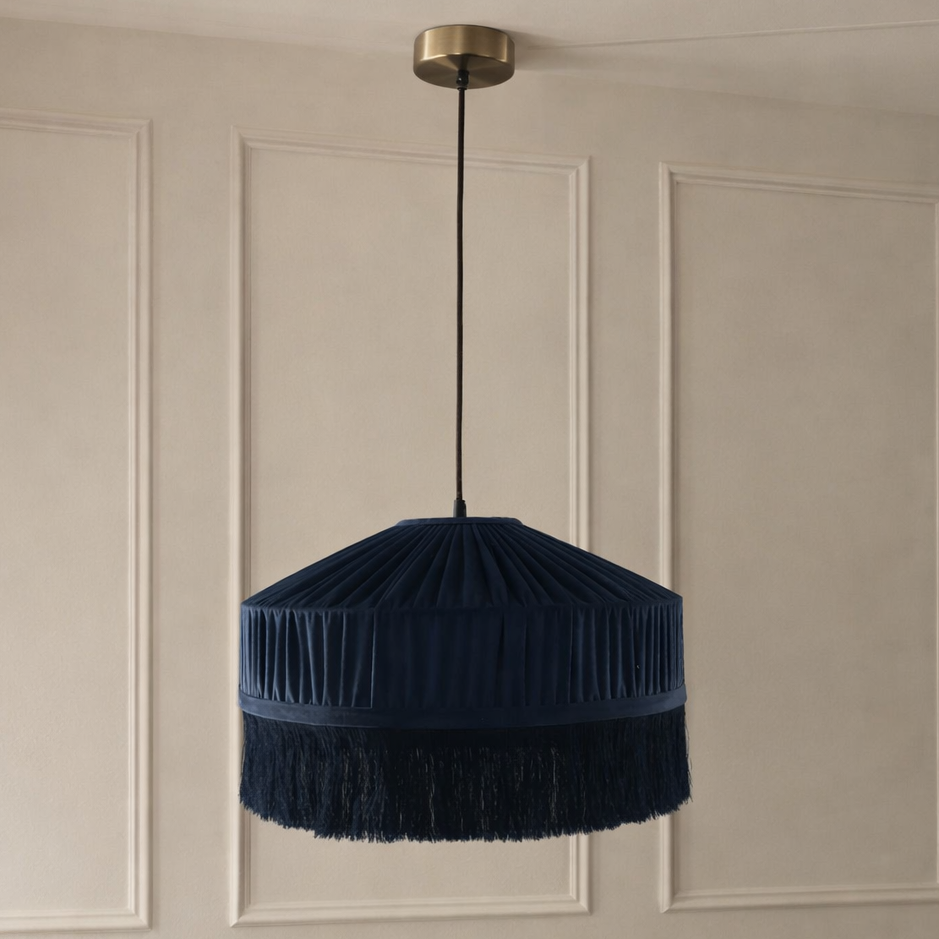 Navy blue pendant light with fringes hanging against a beige wall.